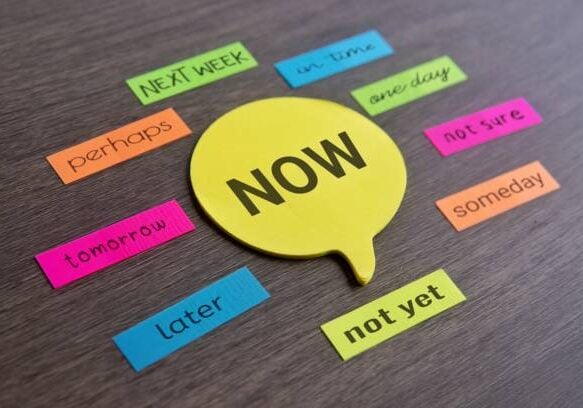 Speech bubble with text NOW surrounded by excuses on colorful sticky note. Procrastinate and urgency concept.
